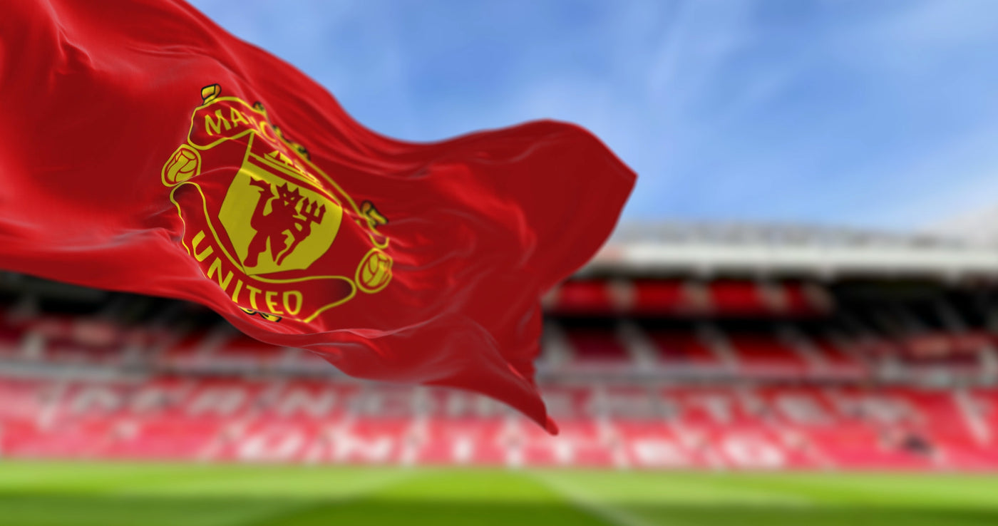 A red Manchester United Flag flying at the stadium, the seats are blurred out in the background