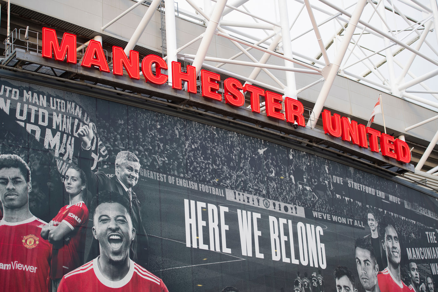 an image of the outside of the Manchester United stadium focussing on a banner saying 'here we belong'